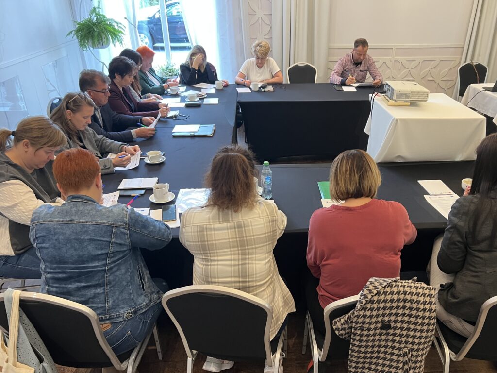 Uczestnicy spotkania zebrani przy stole w jasnej sali konferencyjnej.