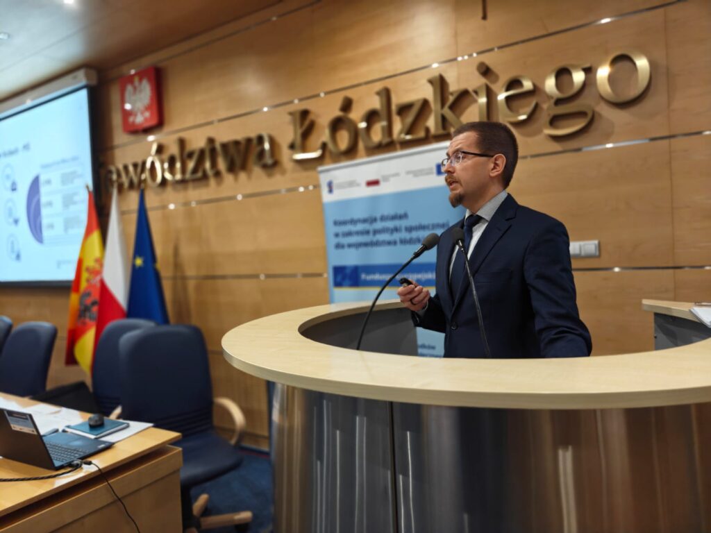 5.	Mężczyzna w eleganckim garniturze wygłasza prezentację przy podium.  