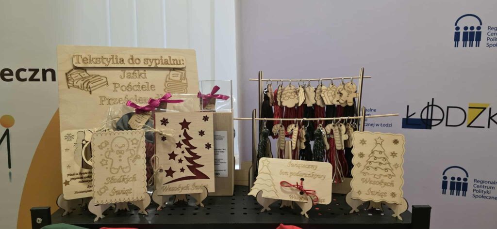 6.	Stół z drewnianymi przedmiotami ozdobionymi świątecznymi dekoracjami wykonanymi przez przedsiębiorstwo społeczne. 