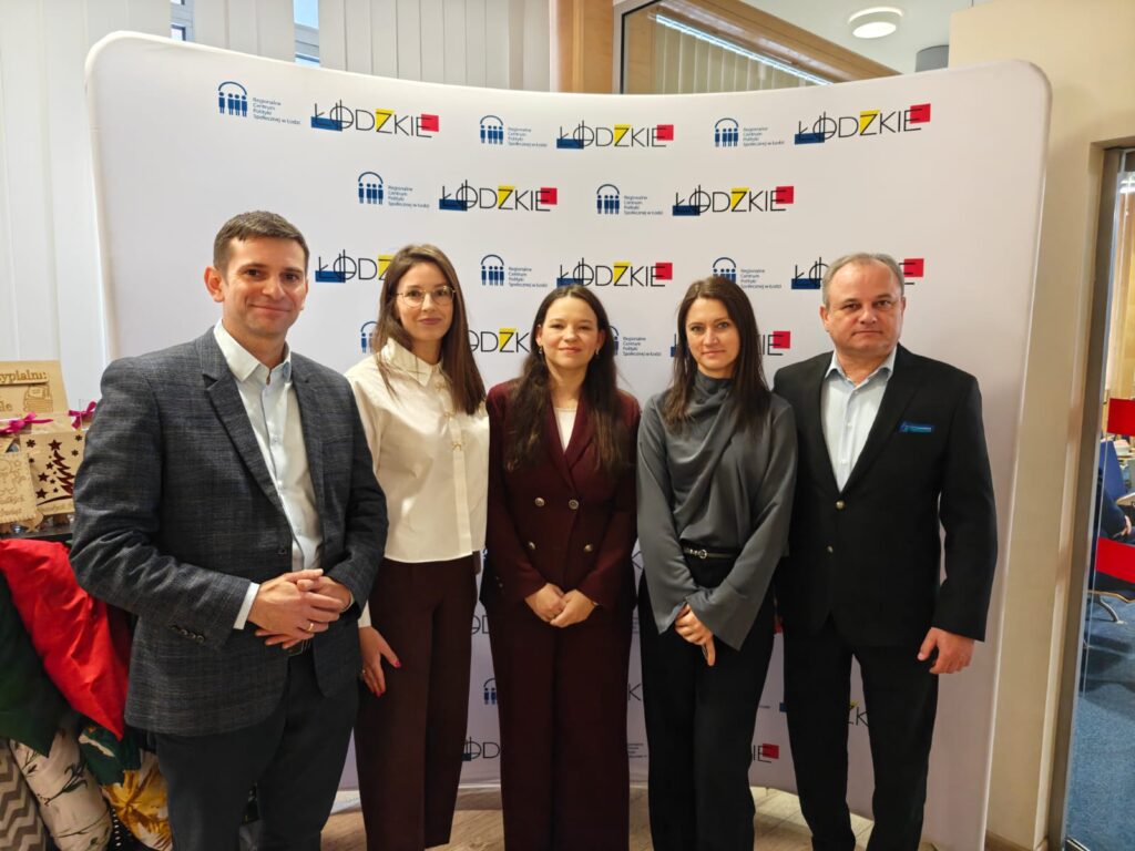 7.	Grupa pięciu ludzi prezentuje się przed banerem z logo.  