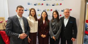 7. Grupa pięciu ludzi prezentuje się przed banerem z logo.