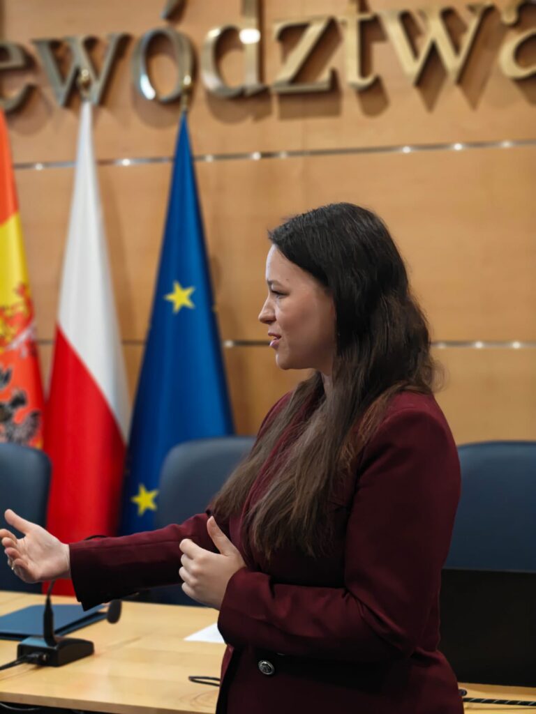 9.	Kobieta w garniturze przemawia przy tym gestykulując. 