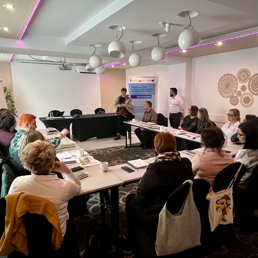 2. Uczestnicy szkolenia siedzą wokół stołu w przestronnej sali spotkań.