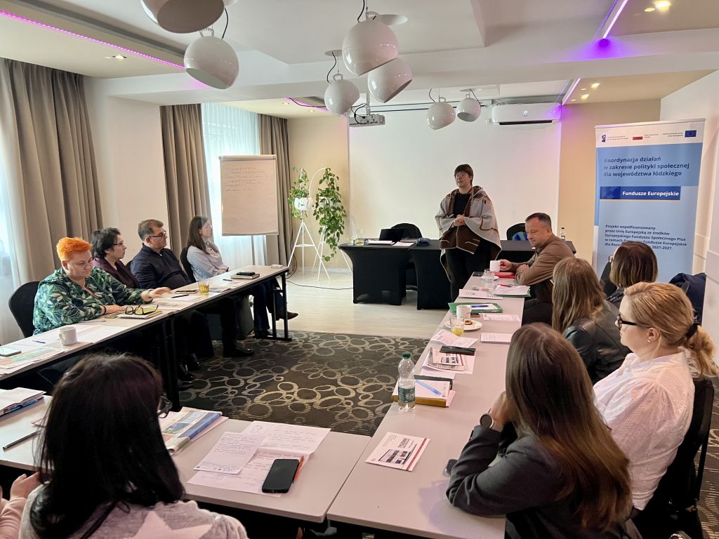 3. Ludzie siedzą przy stołach w pomieszczeniu, tworząc atmosferę spotkania i interakcji