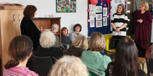 Grupa ludzi siedzi na krzesłach, rozmawiając ze sobą w przyjaznej atmosferze