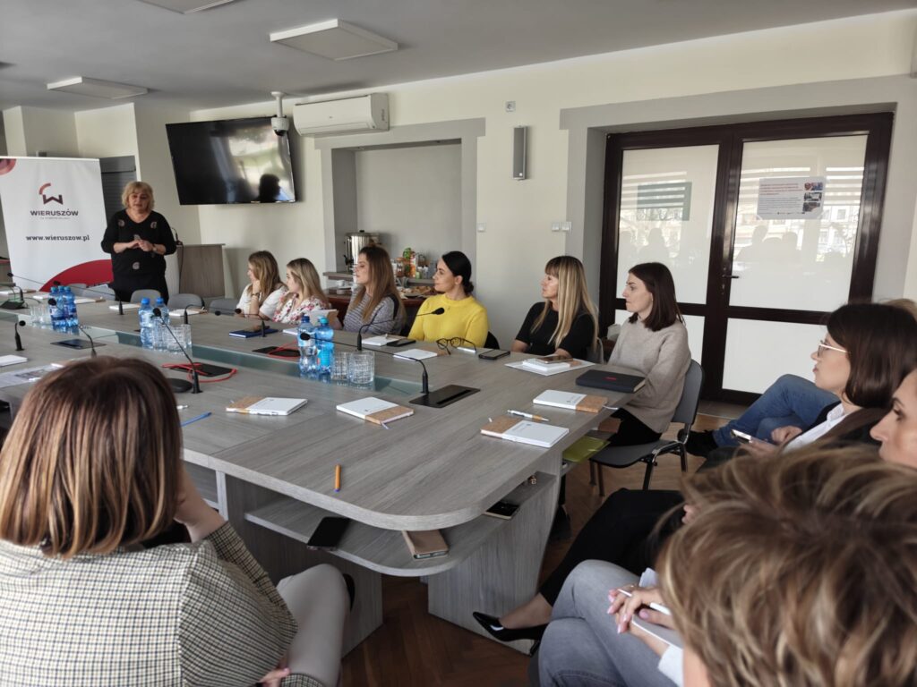 Uczestnicy słuchają prowadzącej spotkanie. 