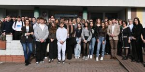 Grupowe zdjęcie młodzieży i organizatorów przed budynkiem szkoły podczas spotkania upowszechniającego ekonomię społeczną w Radomsku