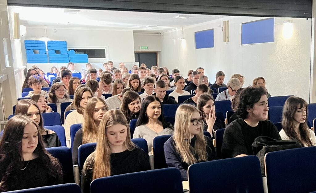 Uczniowie siedzący na widowni podczas spotkania informacyjnego dotyczącego ekonomii społecznej.