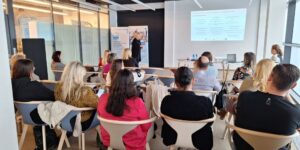 uczestnicy i uczestniczki spotkania wpatrzeni w prezentacje