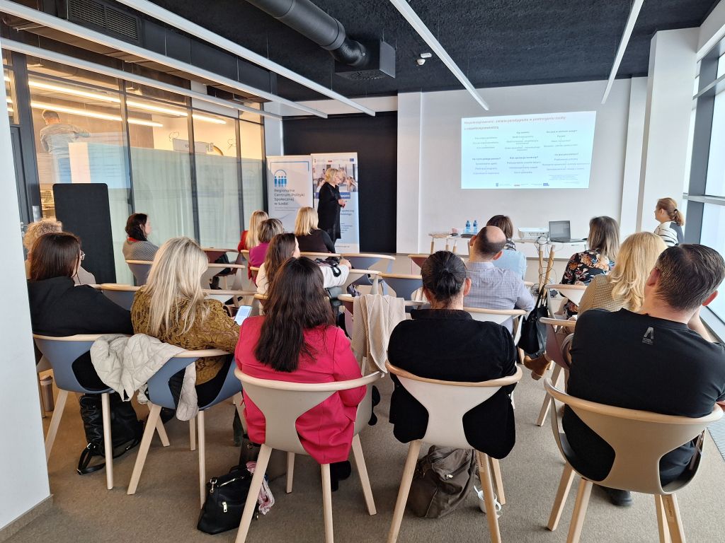 uczestnicy i uczestniczki spotkania wpatrzeni w prezentacje 