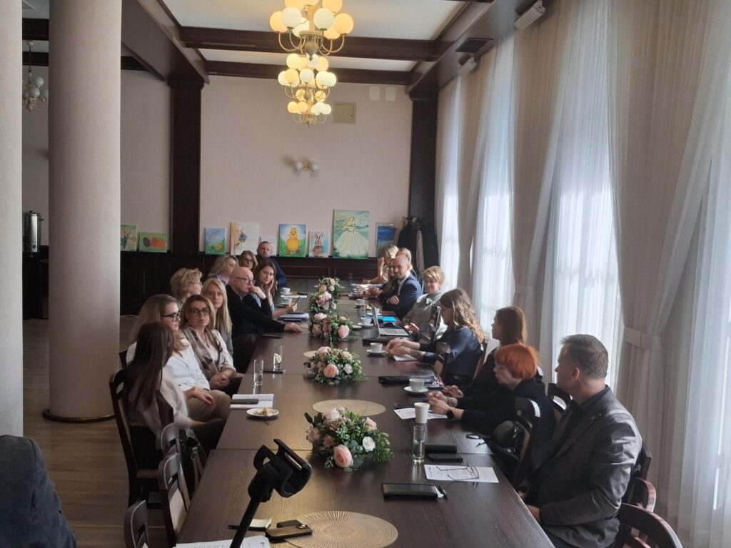 Grupa ludzi siedzi przy długim stole, rozmawiając i dzieląc się pomysłami. (2)