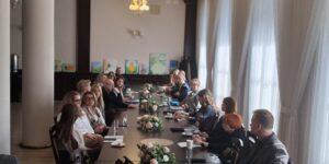 Grupa ludzi siedzi przy długim stole, rozmawiając i dzieląc się pomysłami. (2)