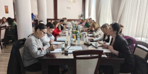 Uczestnicy siedzą przy długim stole ozdobionym kompozycjami kwiatowymi