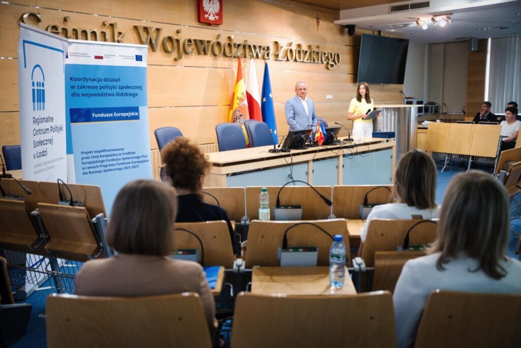 Osoby zgromadzone przed podium, skupione na wystąpieniu mówcy