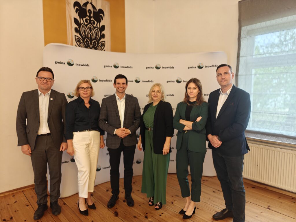 Grupa ludzi stoi przed banerem